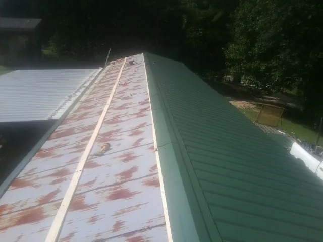 Old rusted panels beside newly installed green metal roofing — Wind Damage Roof Repair by Roofing Brothers in West Dennis