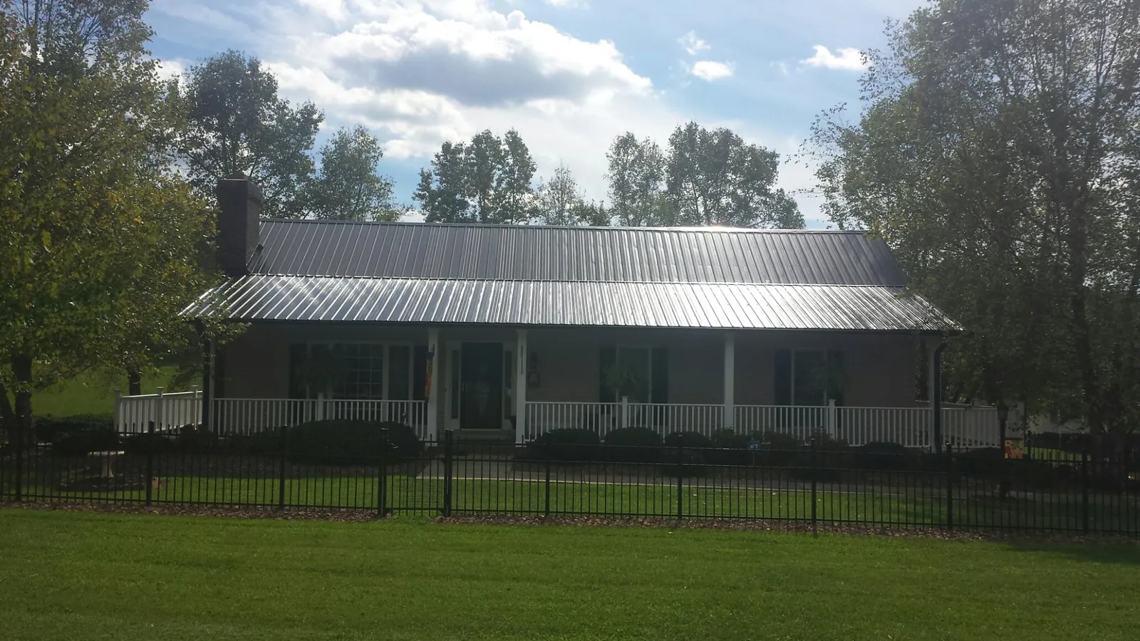 Gray metal roof on a brick ranch with a full width front porch — Gutter Guard Installation work by our crew in West Dennis