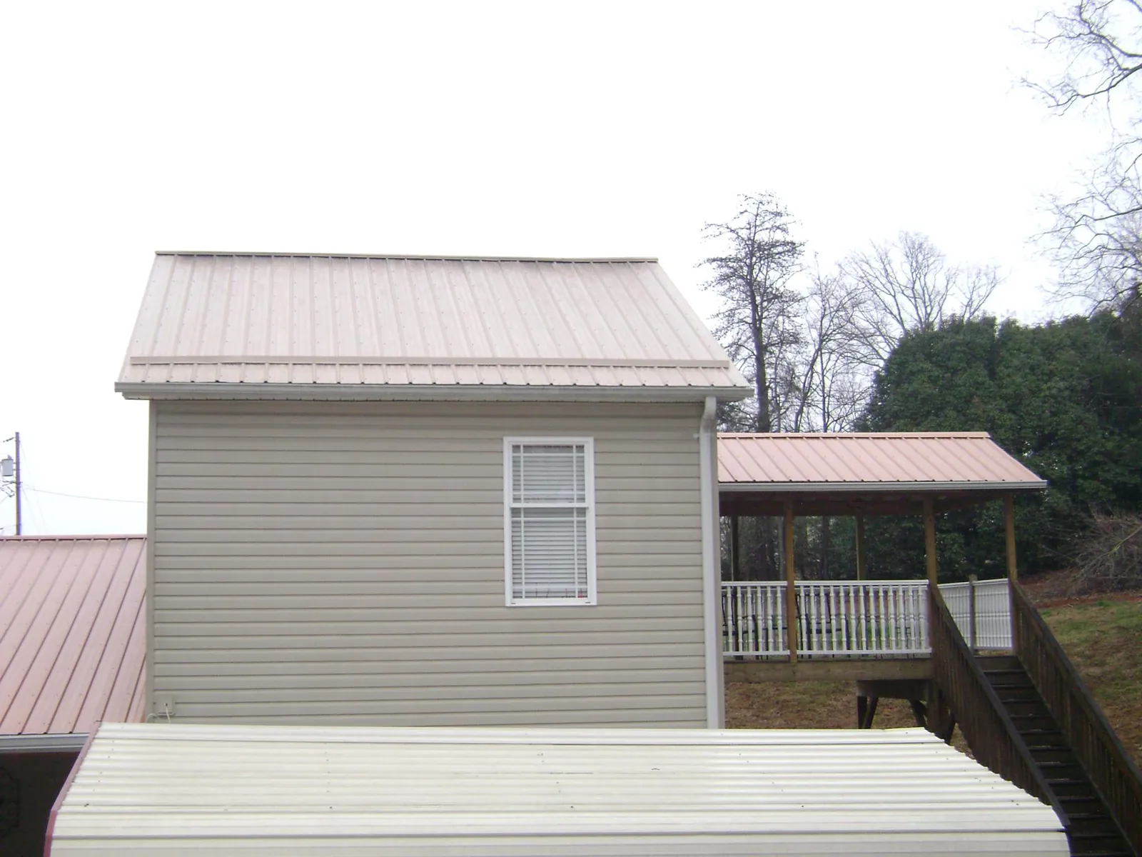 Tan metal roofs on a two story addition and attached porch, from a Roof Replacement job in West Dennis