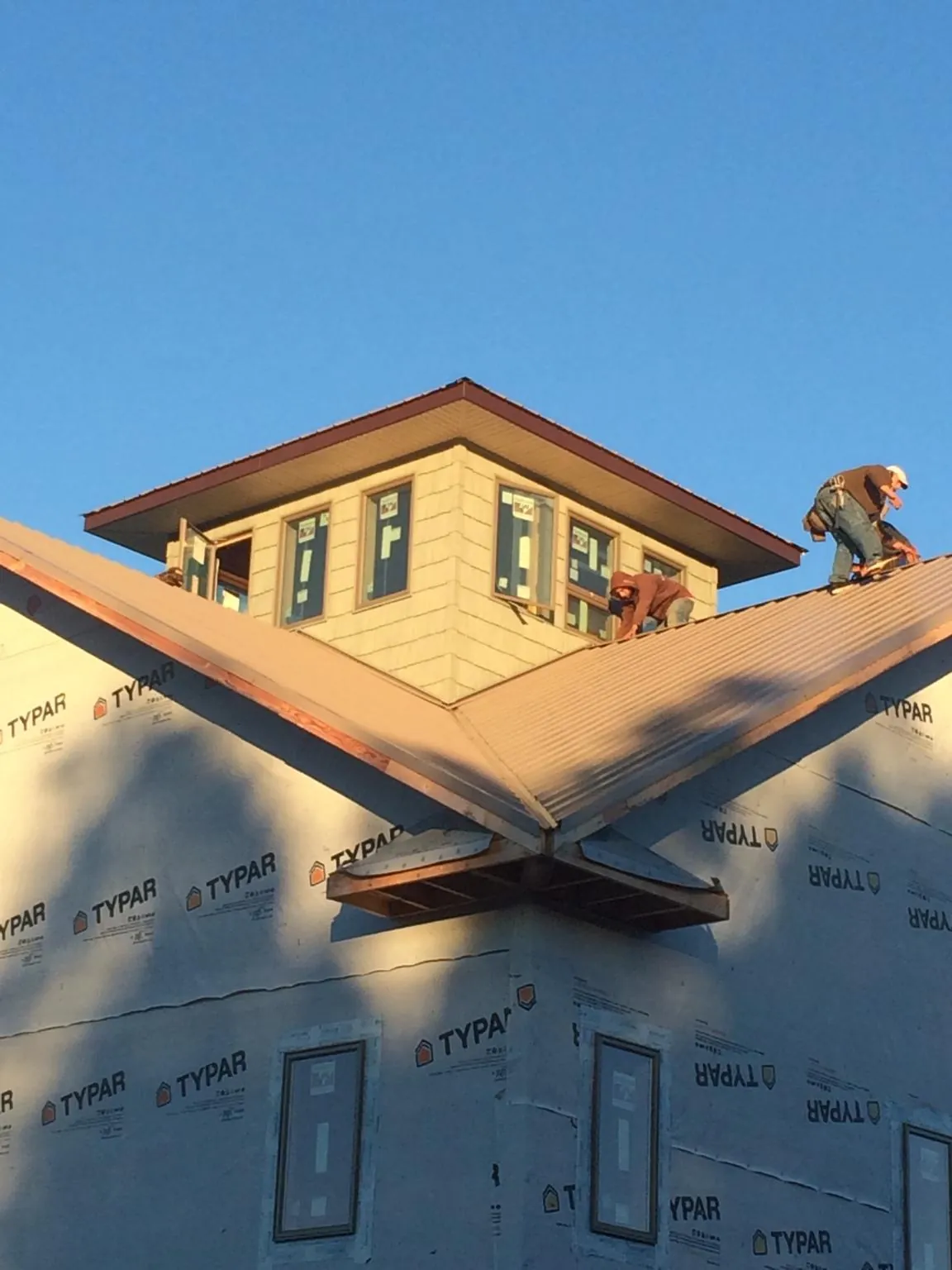 Roofers working around a rooftop cupola on a new metal roof at sunset — Roof Waterproofing in West Dennis by Roofing Brothers